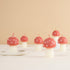 Red and white polka dot mushroom-shaped candles on a beige background.