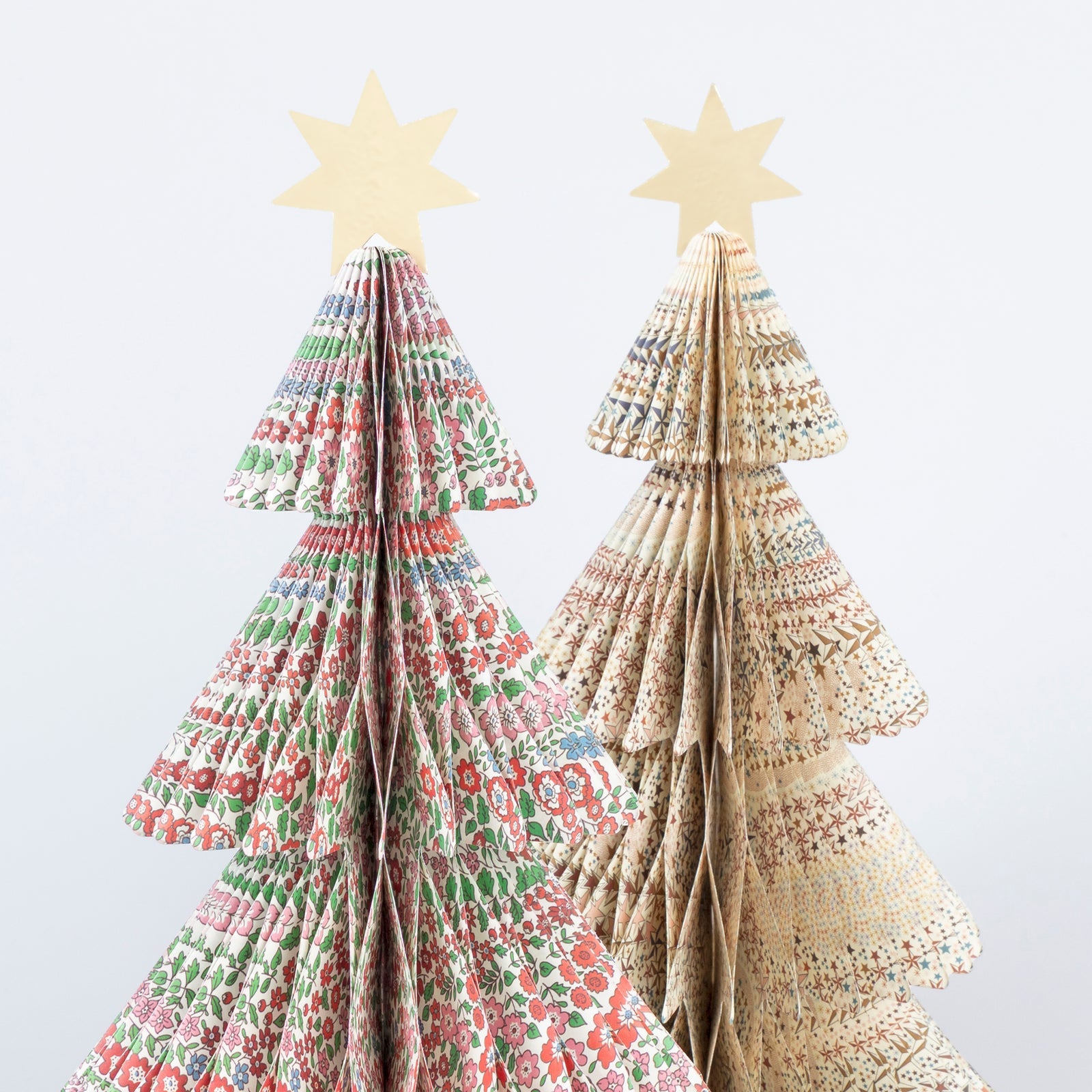 Two paper Christmas trees with star toppers on a white background. 