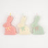 Three bunny-shaped candles in pastel colors with embossed faces and hand-painted bows.