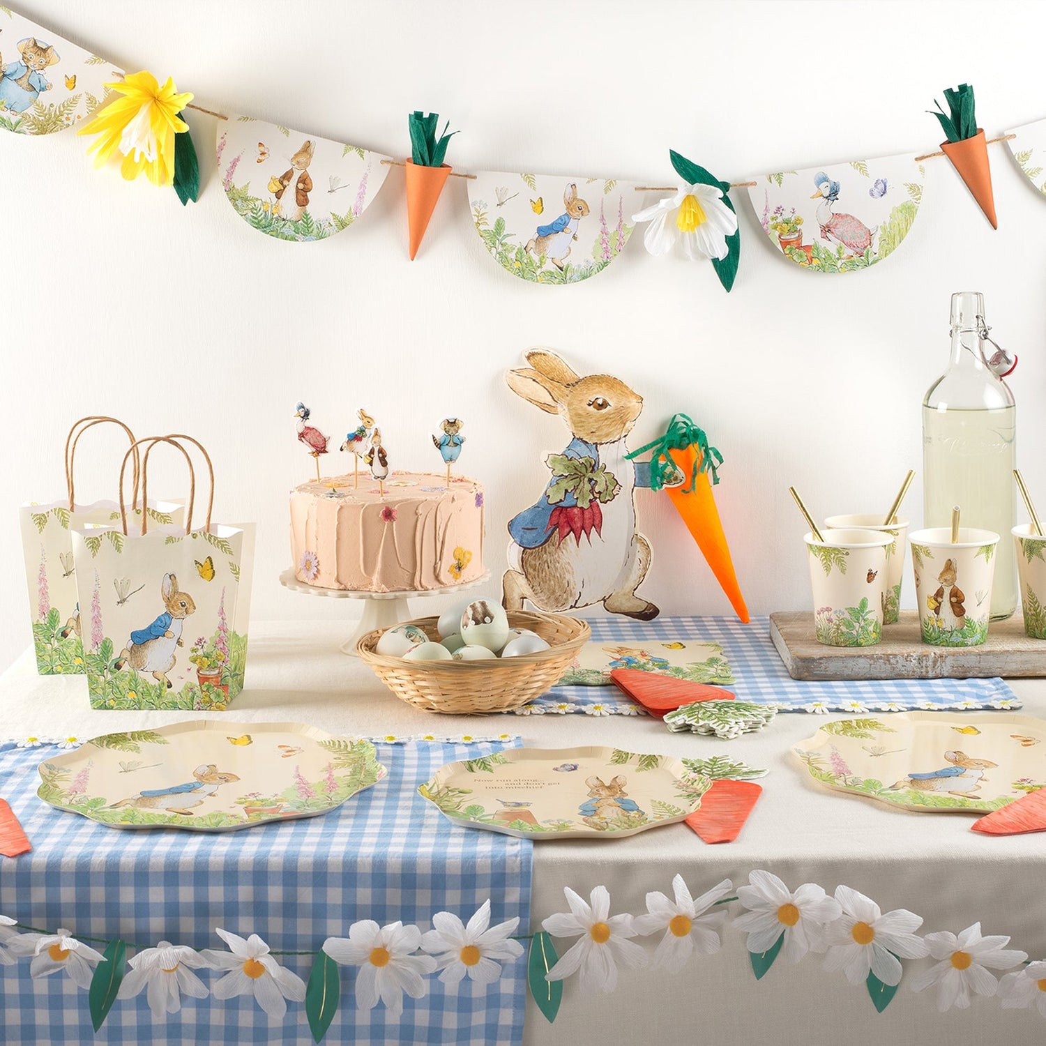A festive table adorned with bunny decorations and Easter party supplies such as a Meri Meri Peter Rabbit in the Garden Garland and party centerpiece.
