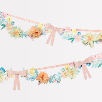 A Meri Meri Flower &amp; Bow Garland adorned with delicate pink flowers and charming bows.