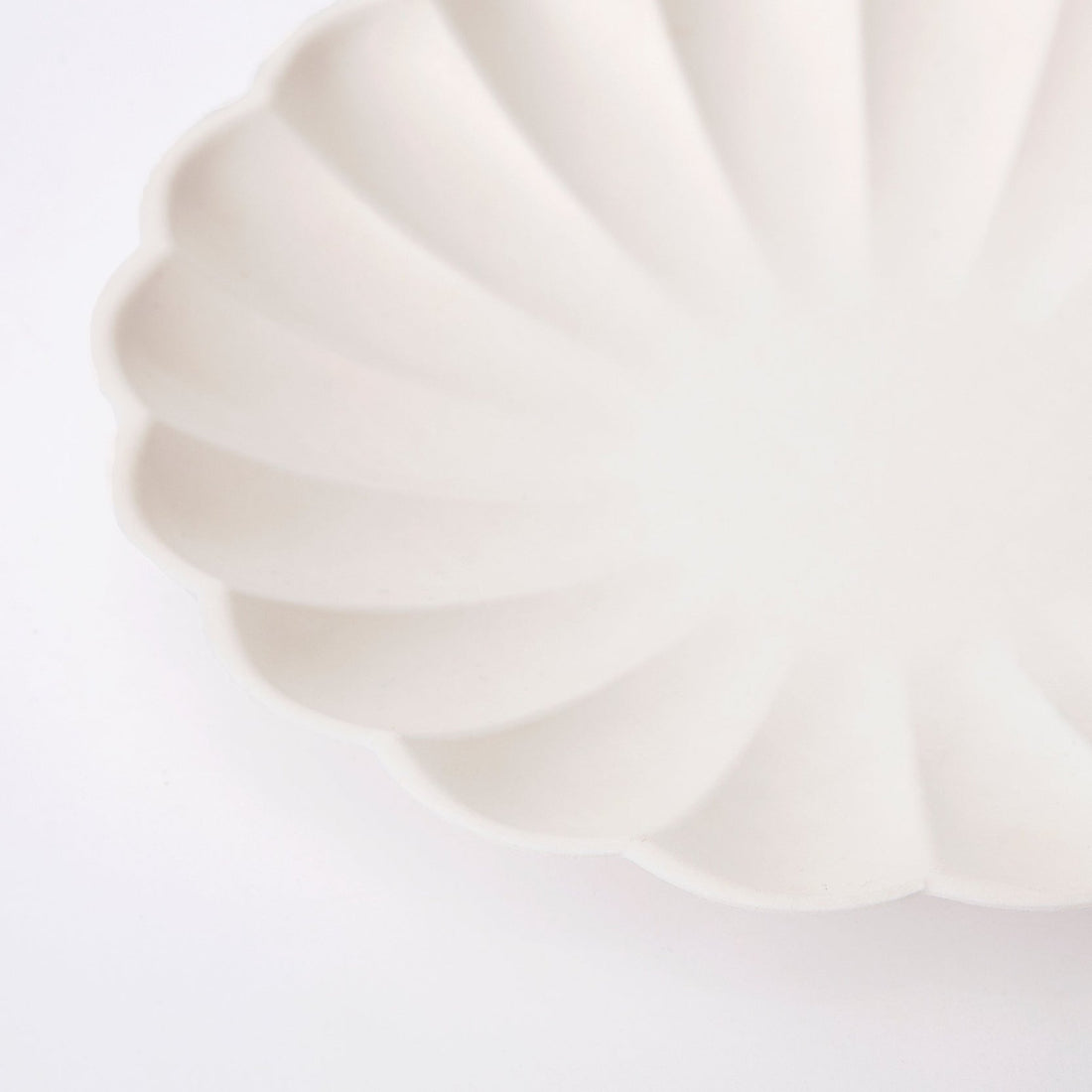 A Meri Meri cream eco plate with a scalloped edge.