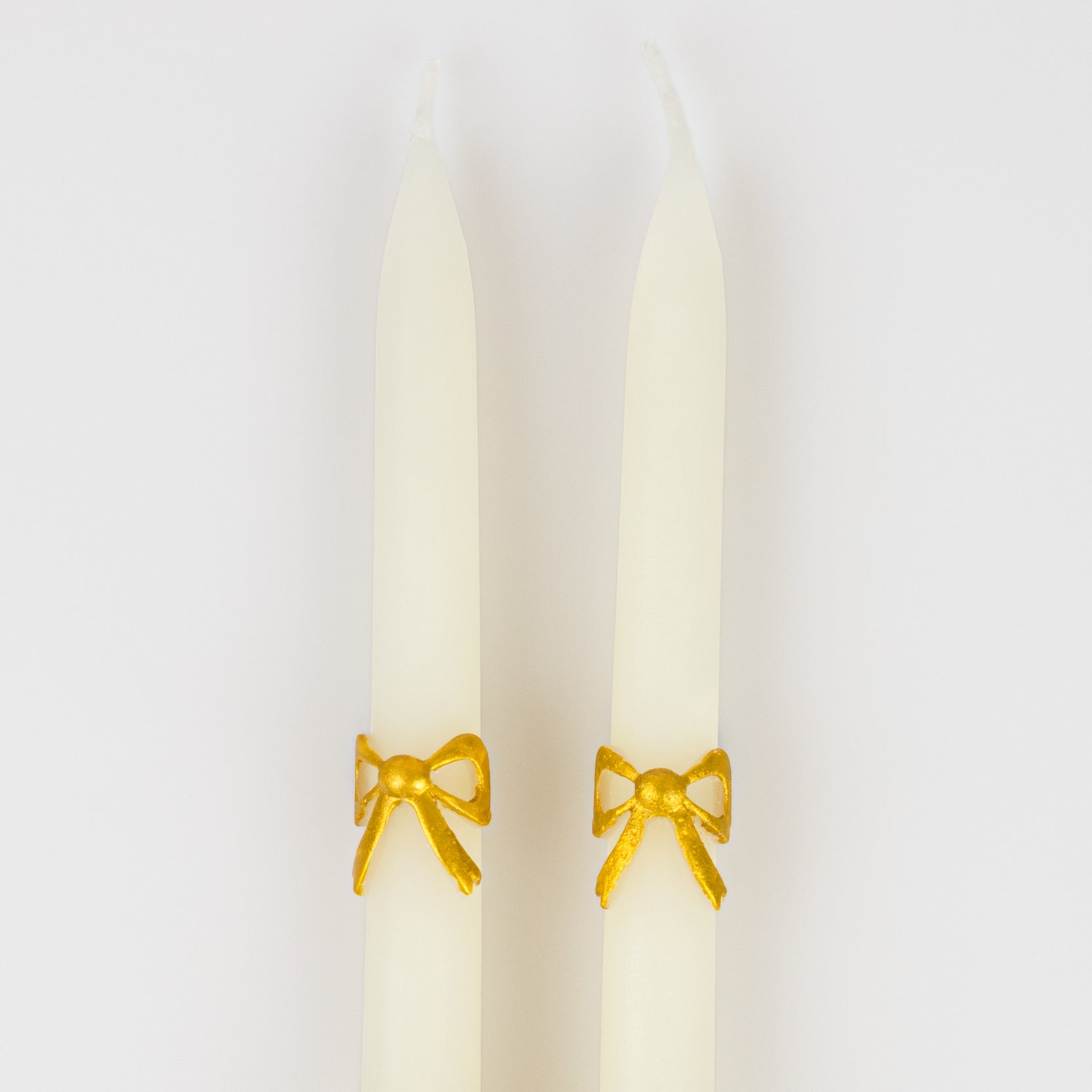 close up of gold bow on taper candles