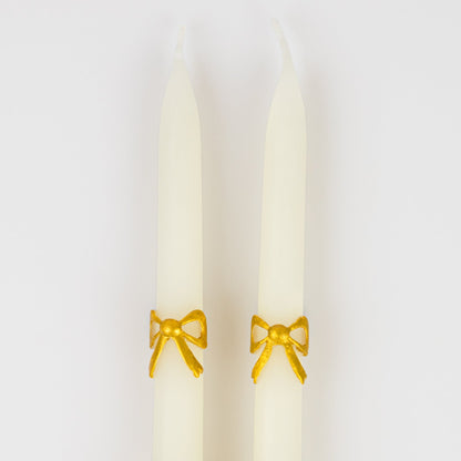 close up of gold bow on taper candles