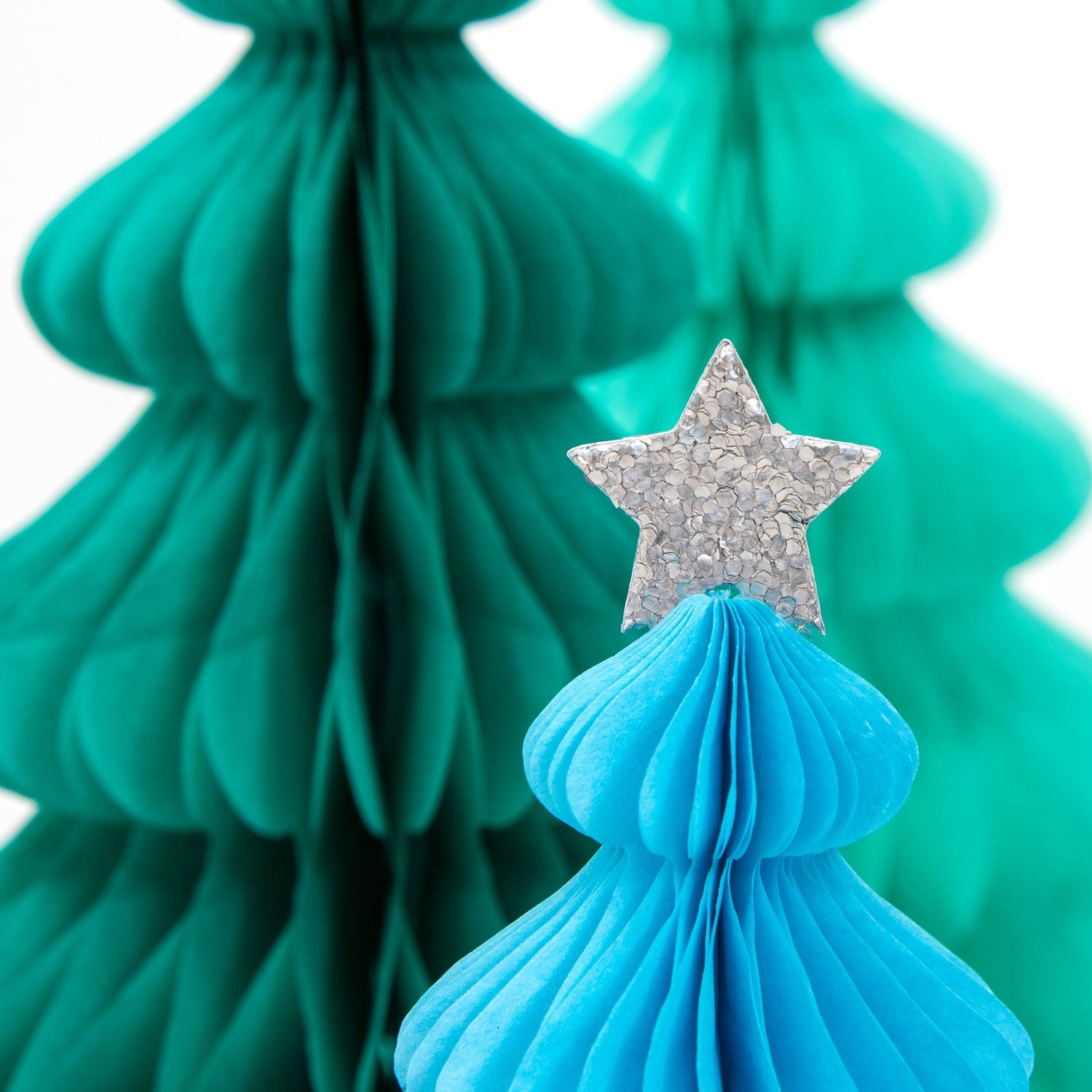 Decorative paper tree with a star on top against a blurred green tree background