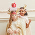Two children wearing festive outfits with reindeer antlers and gift boxes on a decorative background.