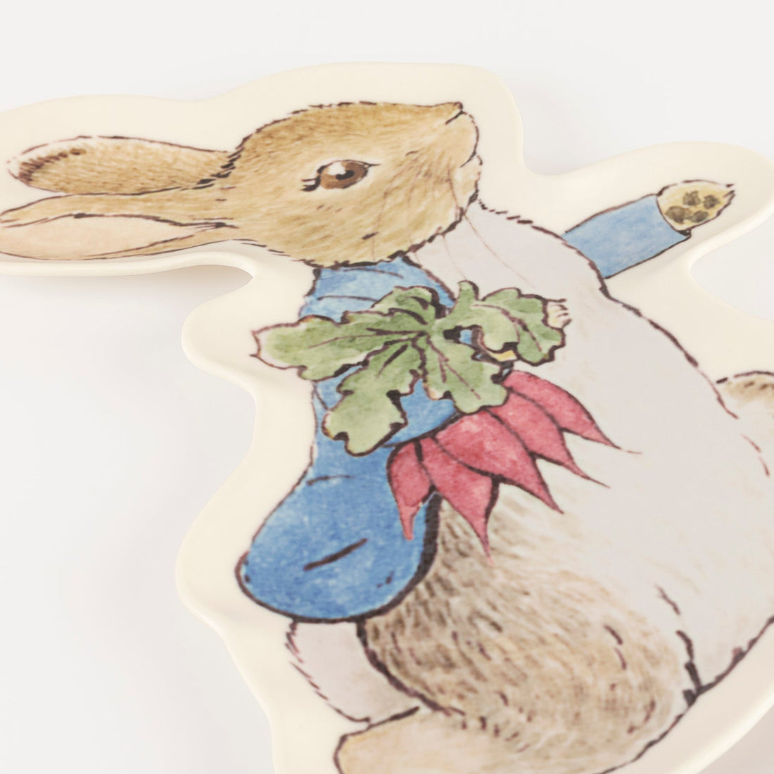 A close-up of a plate shaped and illustrated like Peter Rabbit laid flat against a white background.