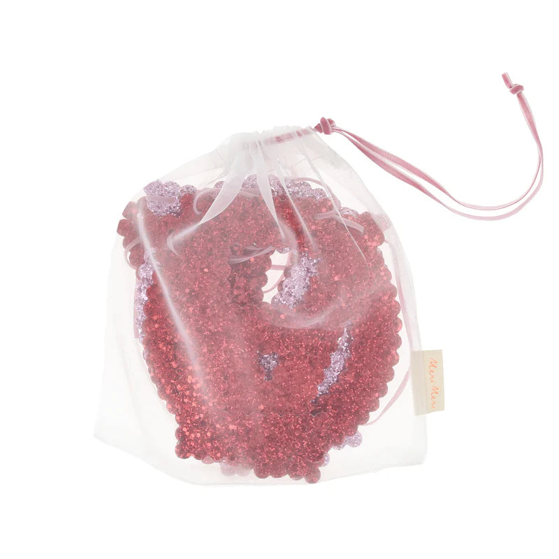 Clear drawstring bag filled with red beads on a white background