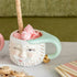 Two Mint/Pink Papa Noel mugs with cookies on a table by Glitterville.