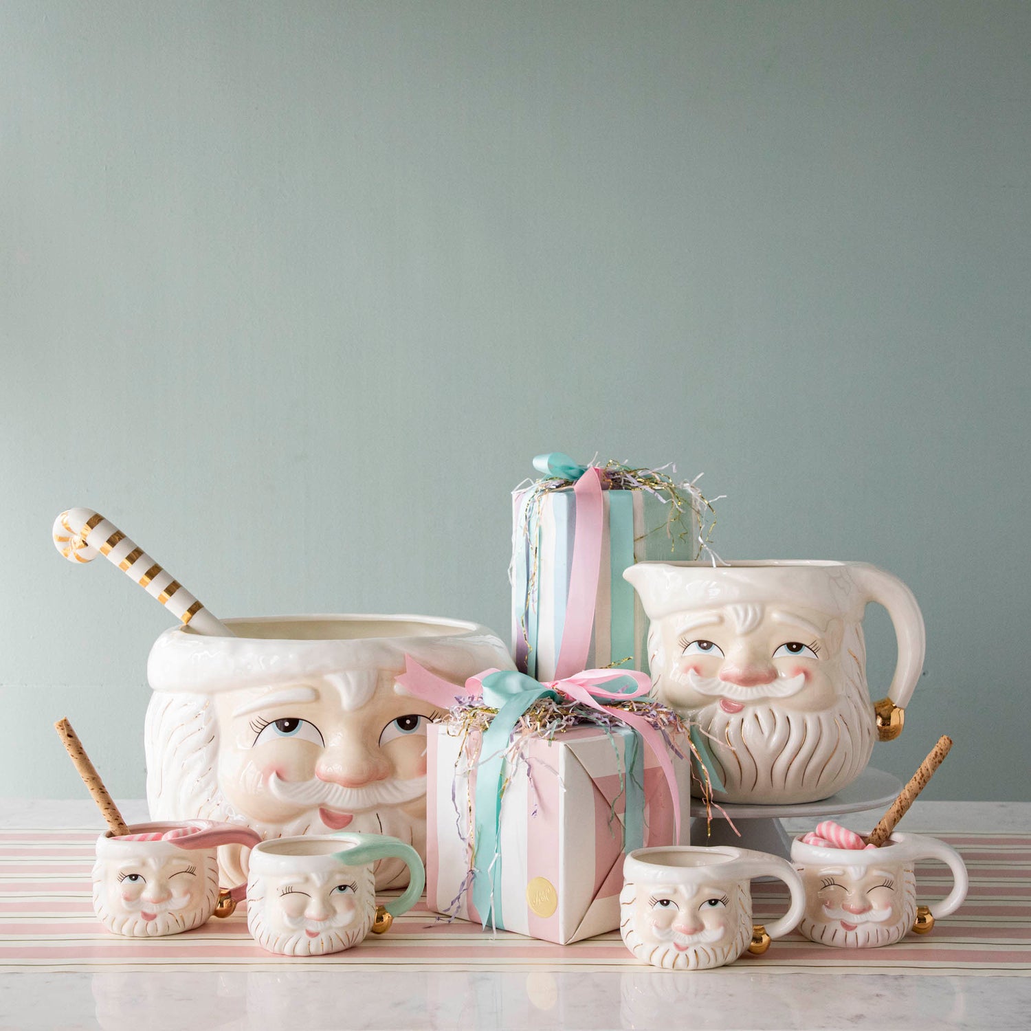 The Papa Noel Pitcher, punch bowl and mugs, displayed on a table with presents.