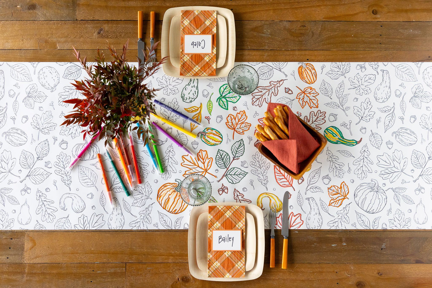 A fall tablescape featuring a partially colored in Autumn Coloring Runner, with colorful markers scattered on the table.