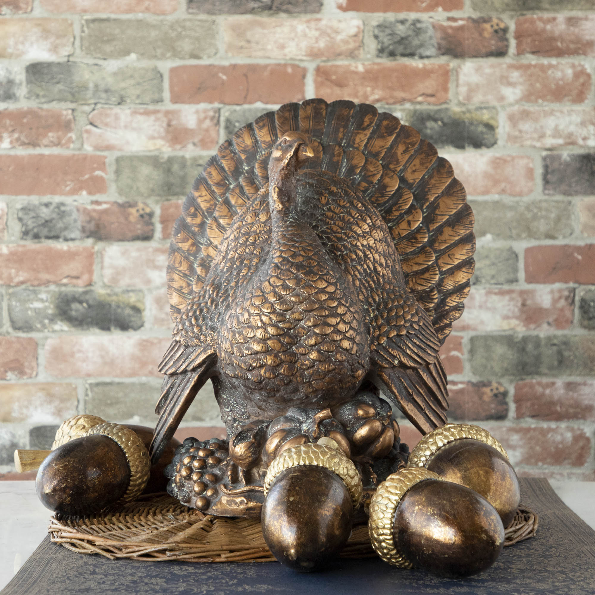 The Antiqued Bronze Turkey Centerpiece surrounded by brass acorns on a table.