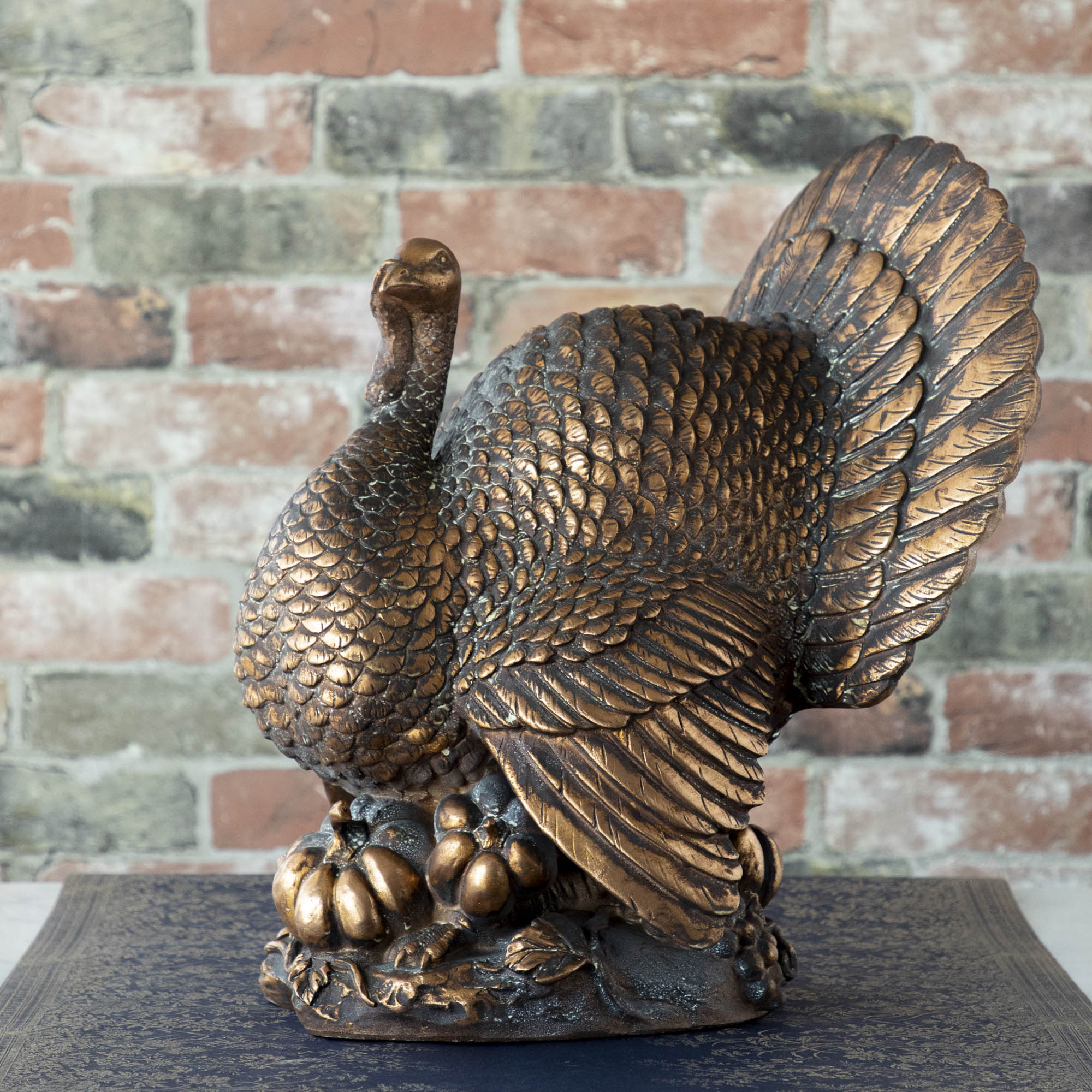 An Antiqued Bronze Turkey Centerpiece with intricate detailing and pumpkins near its base.