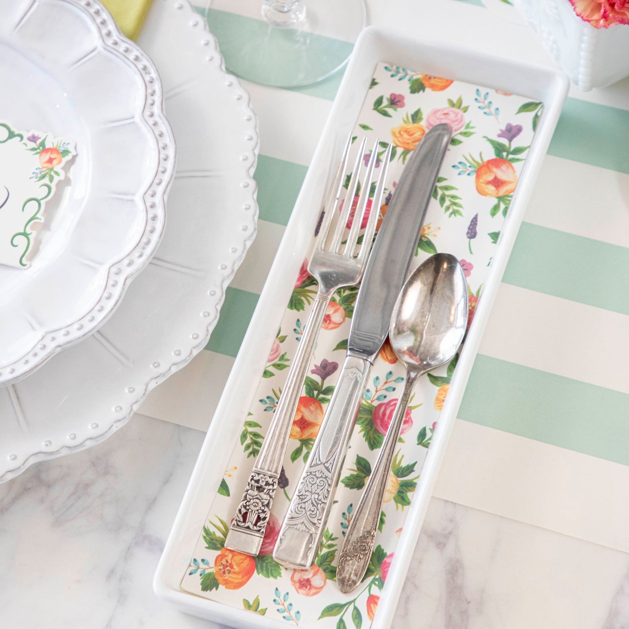 Close-up of a flatware tray lined with a cut-out rectangle of the Sweet Garden Placemat, used in an elegant springtime place setting.