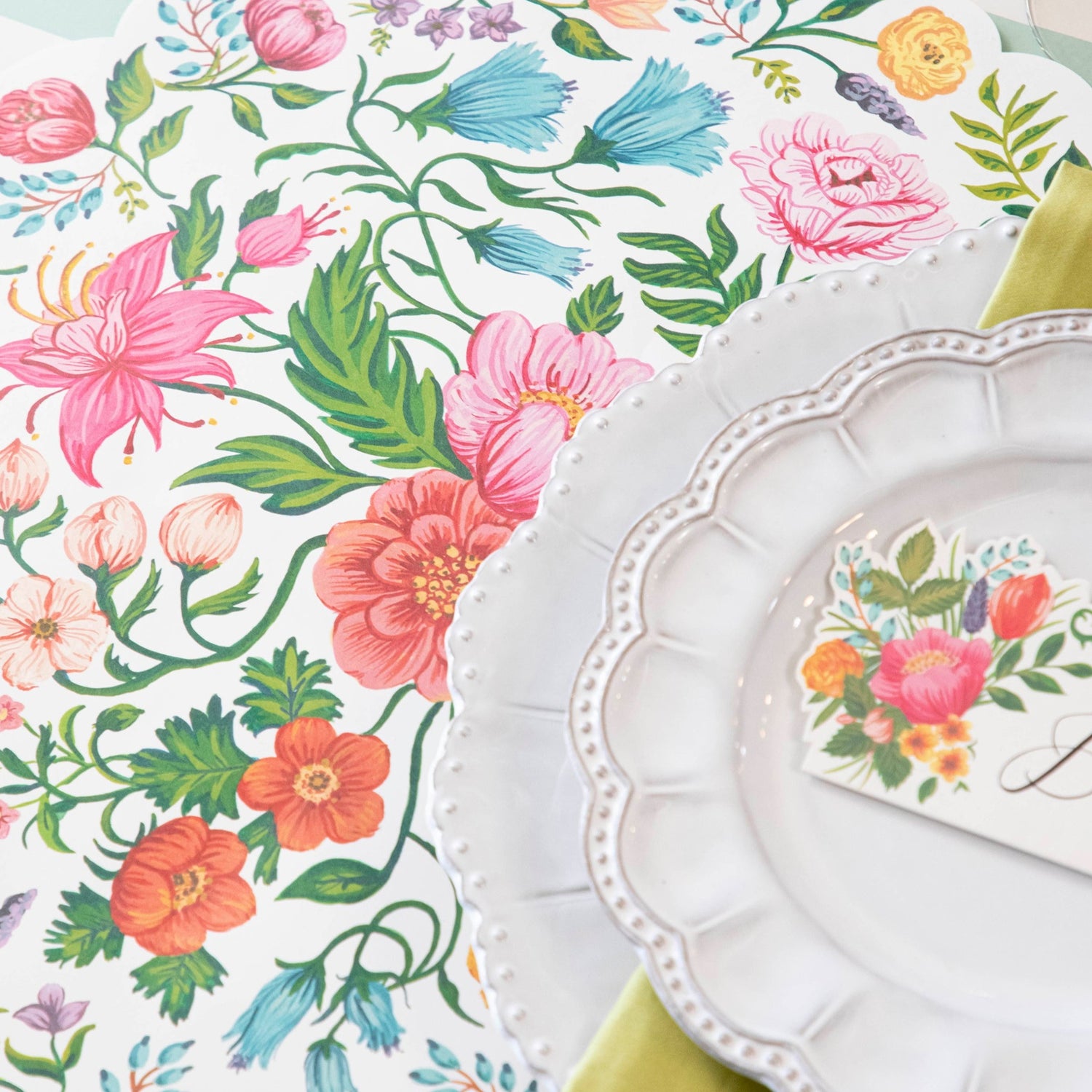A plate with Die-cut Sweet Garden Posey Placemats adorned with colorful blooms from Hester &amp; Cook.