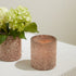 One Pink Shimmer Votive with flowers in it and another with a lit candle.