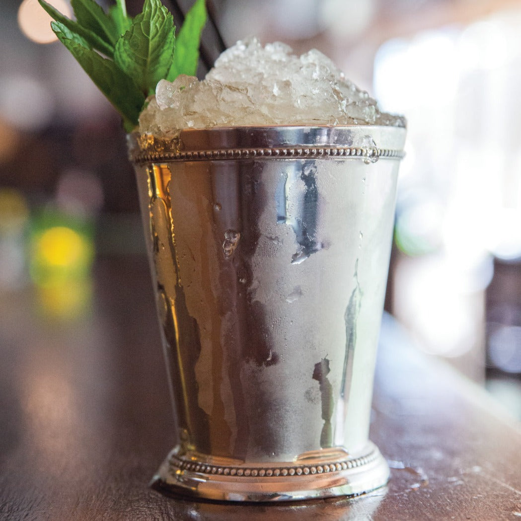 An iced mojito in a Truebrands mint julep cup on a table.