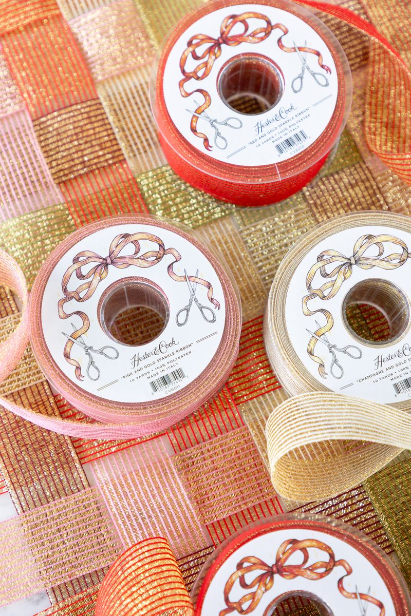 Several spools of sparkly ribbon in various colors unraveled on a surface of woven sparkle ribbon. 
