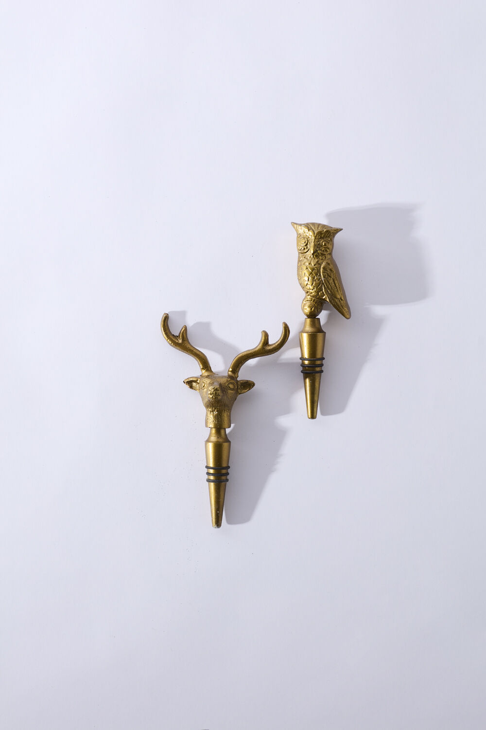 Two gold deer head bottle stoppers on a white background.