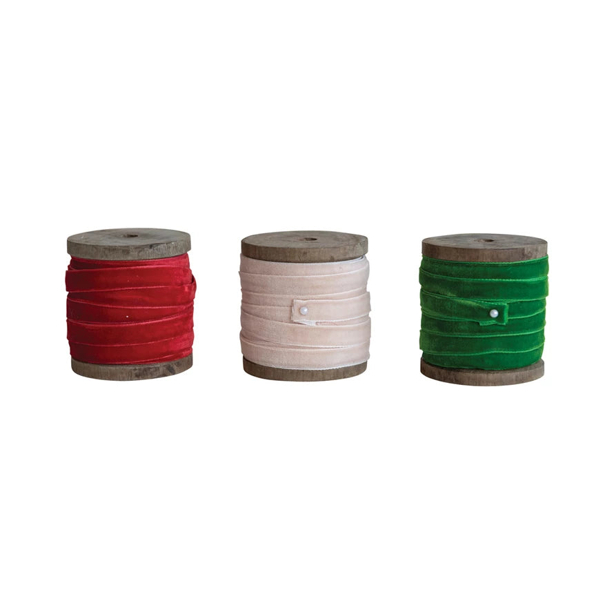 Three spools of ribbon in red, beige, and green on a white background.