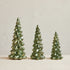 Three green ceramic Christmas trees on a beige surface with a light background