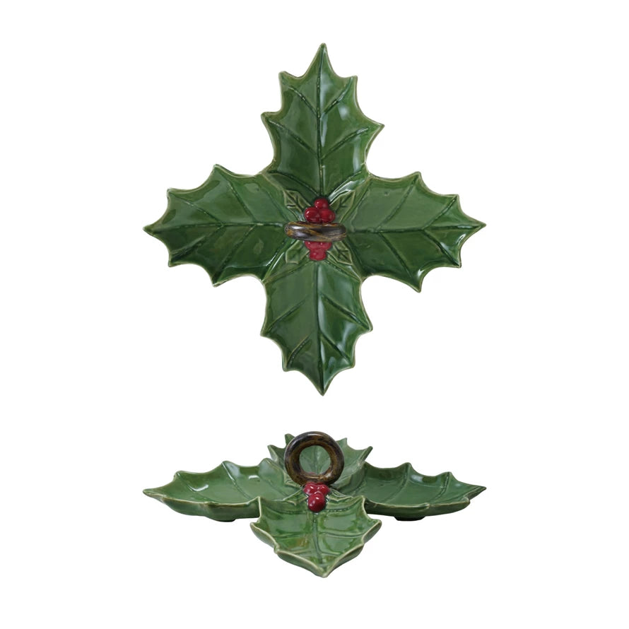 Green holly leaf-shaped dish with red berries and a circular brown handle in the center, on a white background.