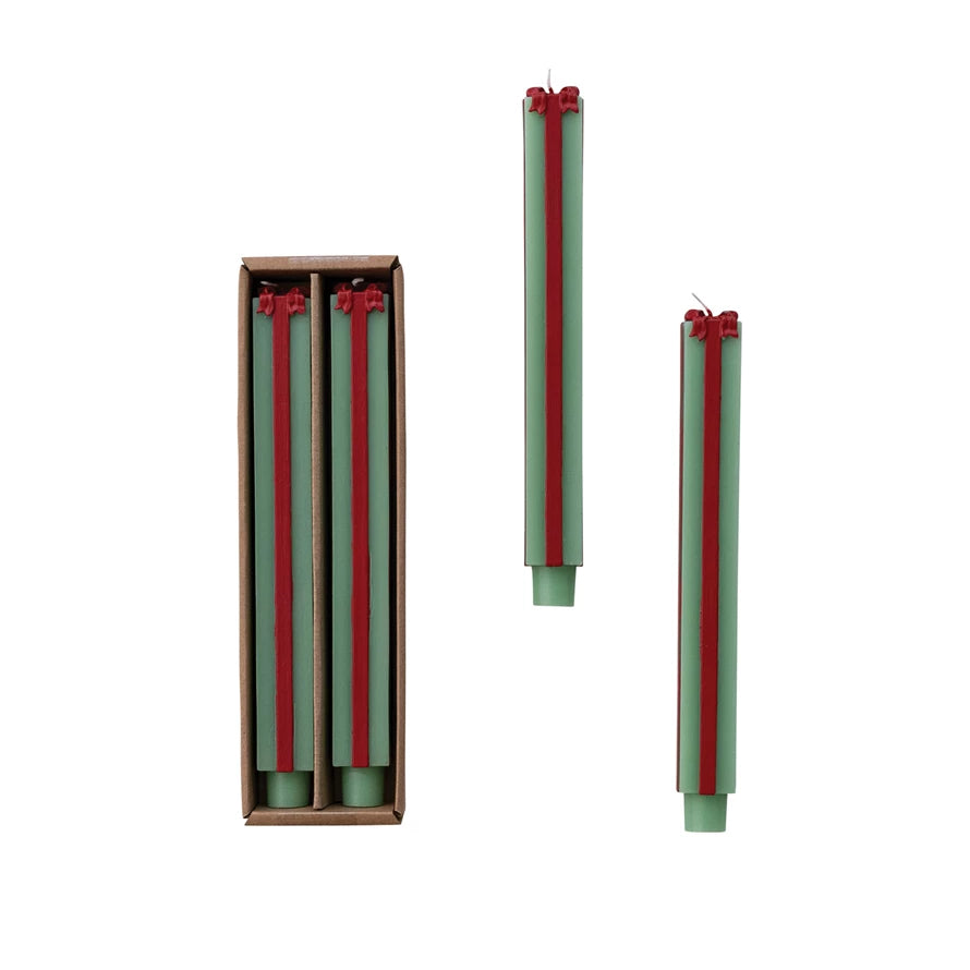 Green candles with red stripes in a cardboard box on a white background