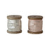 Two wooden spools of metallic ribbon in silver and pink on a white background.