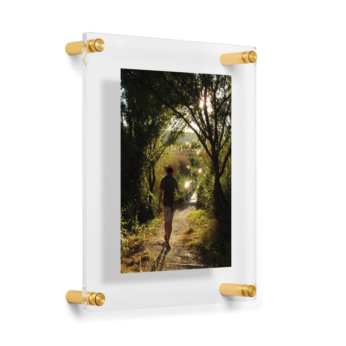 A framed photograph displaying a person walking along a sunlit forest path, encased in Wexel&