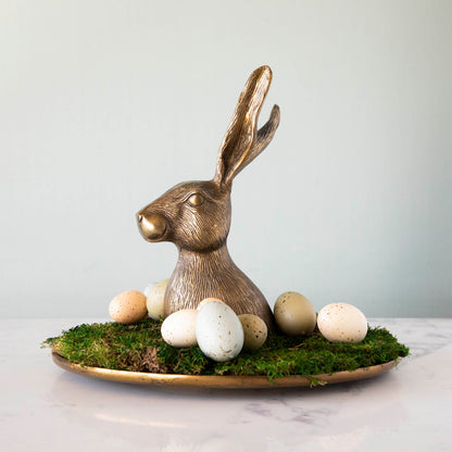 A whimsical gold bunny sits on top of moss and eggs, placed on an Accent Decor Hare Platter.