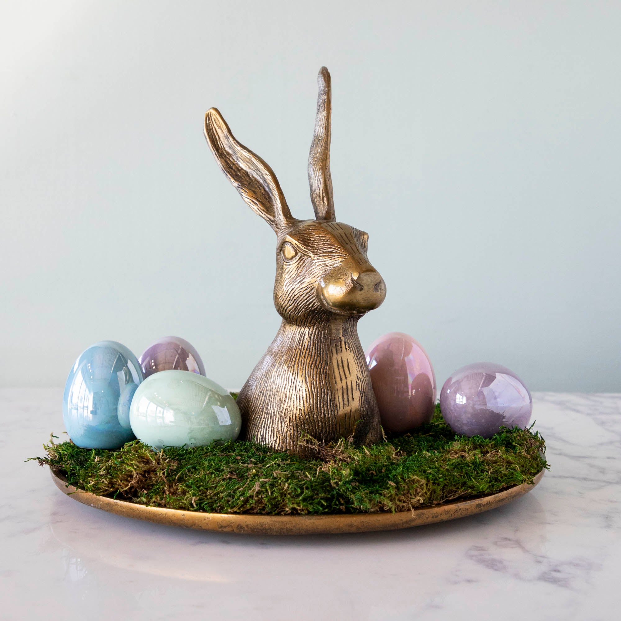 A whimsical gold bunny sits on top of moss and eggs, placed delicately on an Accent Decor Hare Platter.