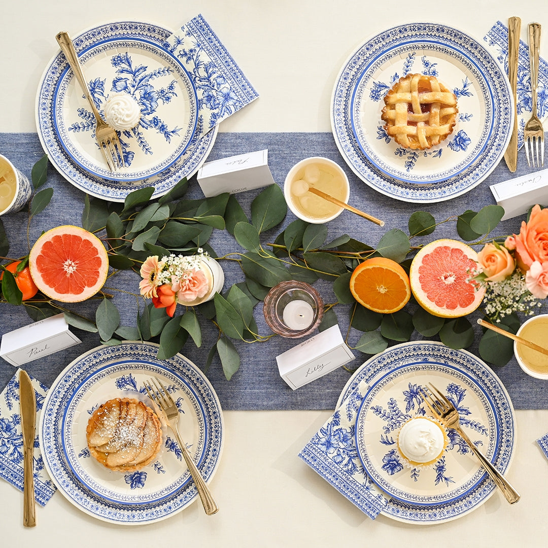 A Blue French Toile Paper Party Dinnerware table setting inspired by the French countryside with oranges and grapes, brought to you by Coterie Party Supplies.