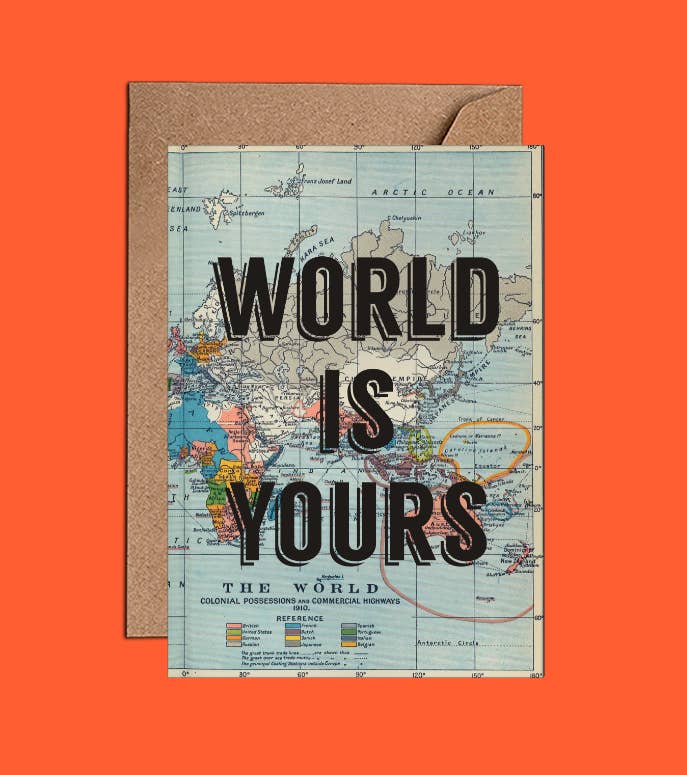 A vintage world map with the phrase &quot;world is yours&quot; superimposed, placed against an orange backdrop with a corner tucked into a brown notebook cover made of recycled paper to create the We Act Company World is Yours Card.