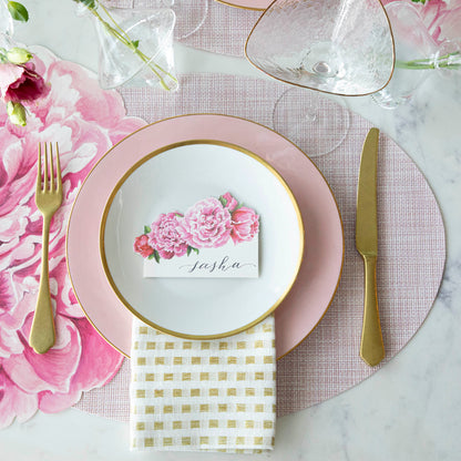 Top-down view of an elegant floral place setting featuring a Peony Place Card labeled &quot;Sasha&quot; laying flat on the plate.