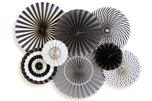 A collection of black and white patterned party fans laid out on a white surface.
