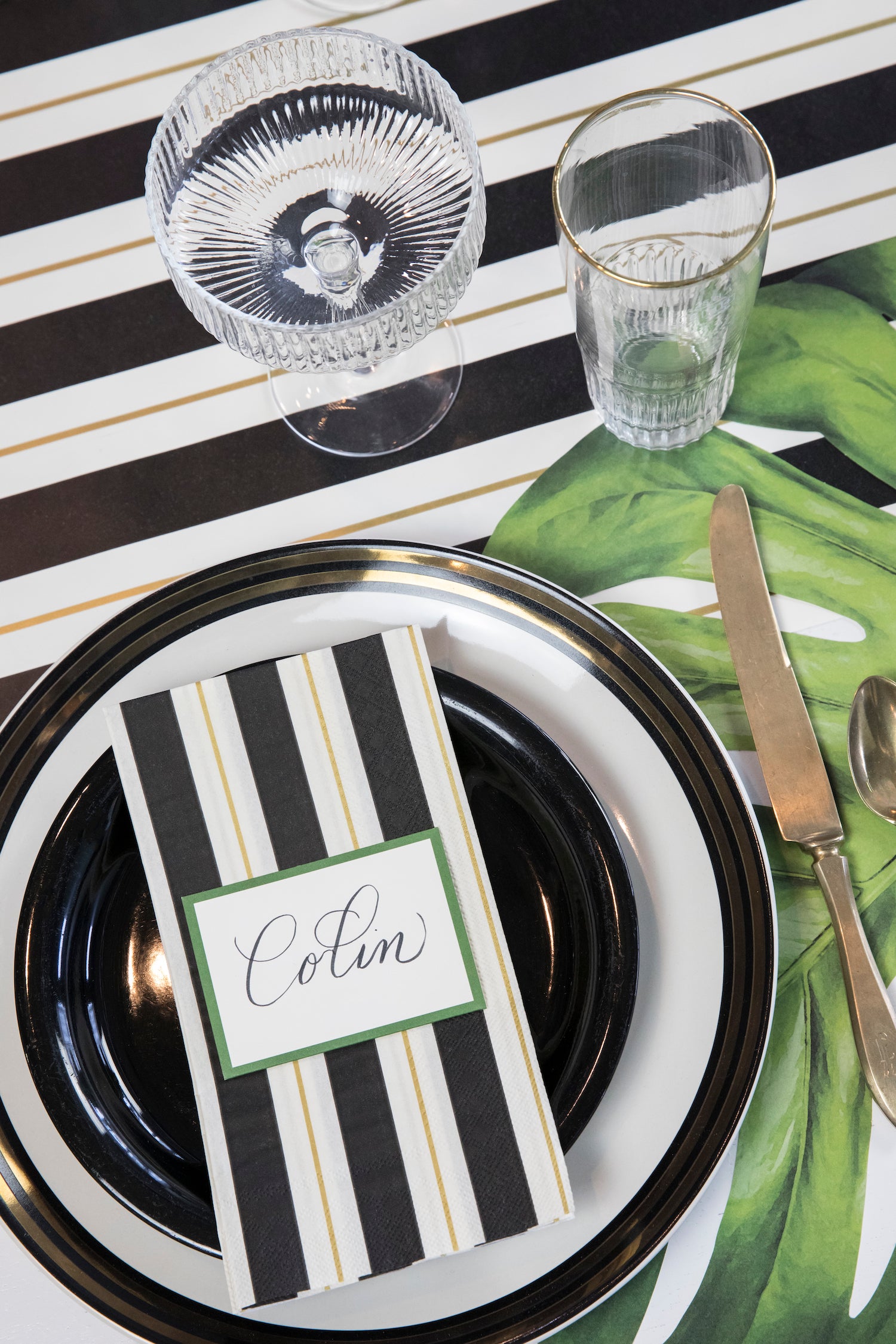 An elegant table setting with a Hester &amp; Cook Black &amp; Gold Awning Stripe Napkins tablecloth, perfect for a party.