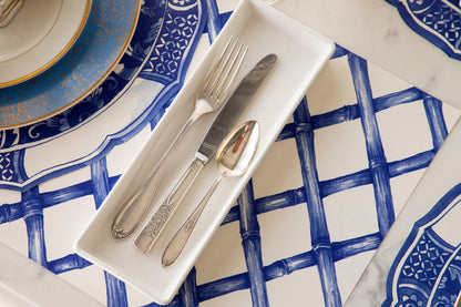 A blue and white table setting with silverware, Hester &amp; Cook bamboo lattice placemat, and paper placemats.