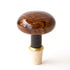 Polished wooden bottle stopper with a cork base featuring a unique Hester & Cook Brown Porcelain Knobstopper against a white background.