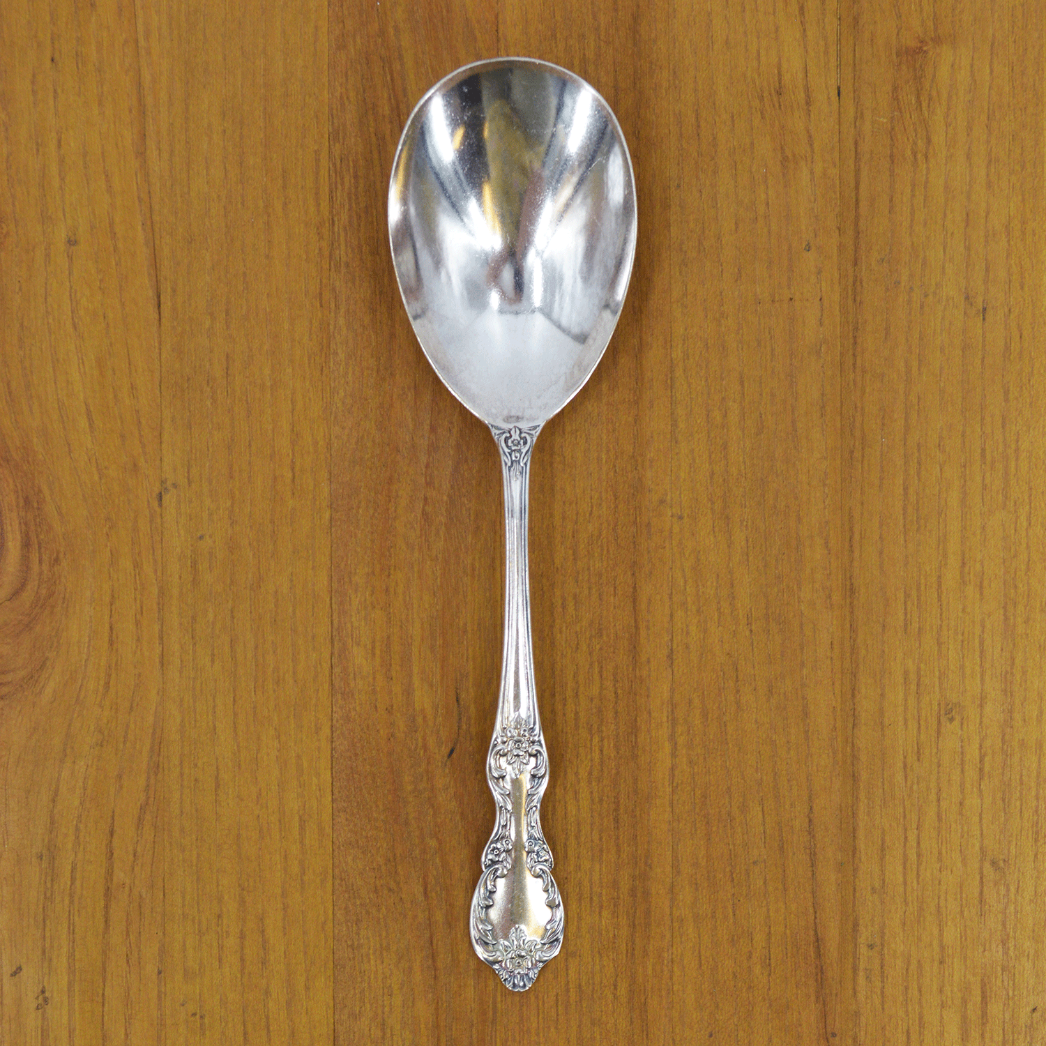 A Hester &amp; Cook Vintage Silver-Plate Berry Spoon on a wooden surface.