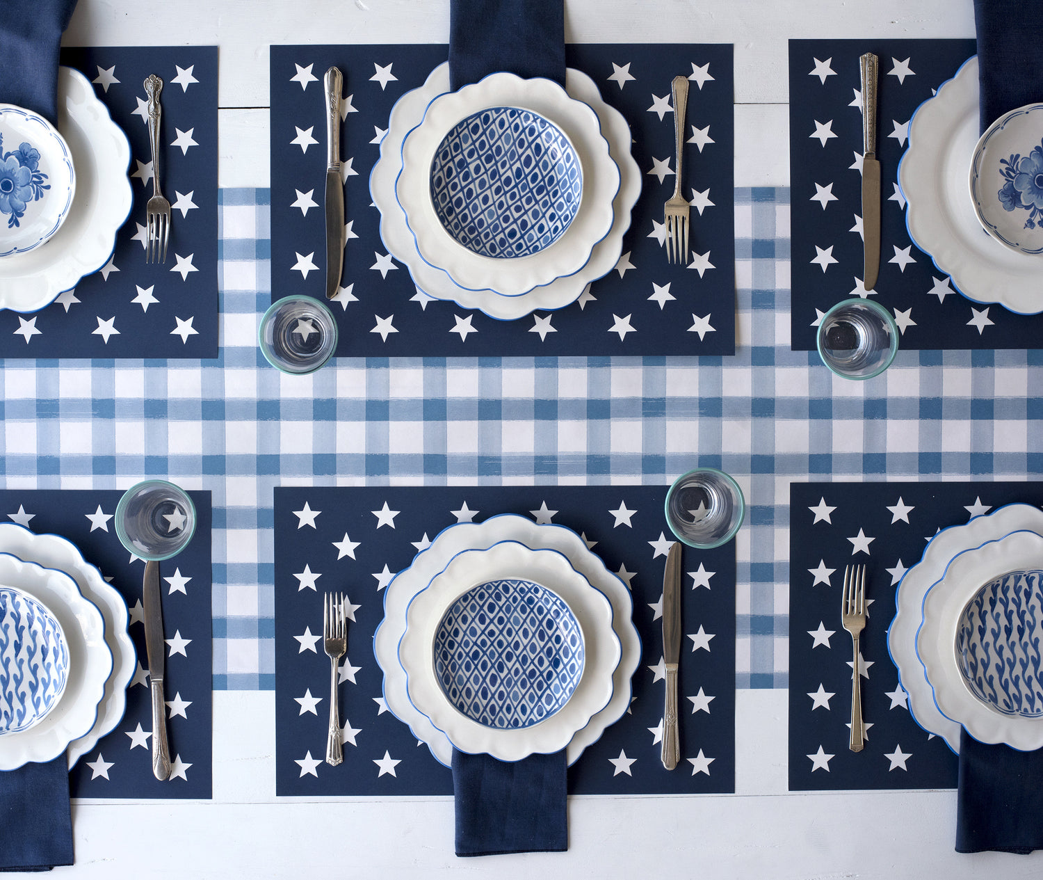 A blue and white tablescape with Stars on Blue Placemats from Hester &amp; Cook and silverware.