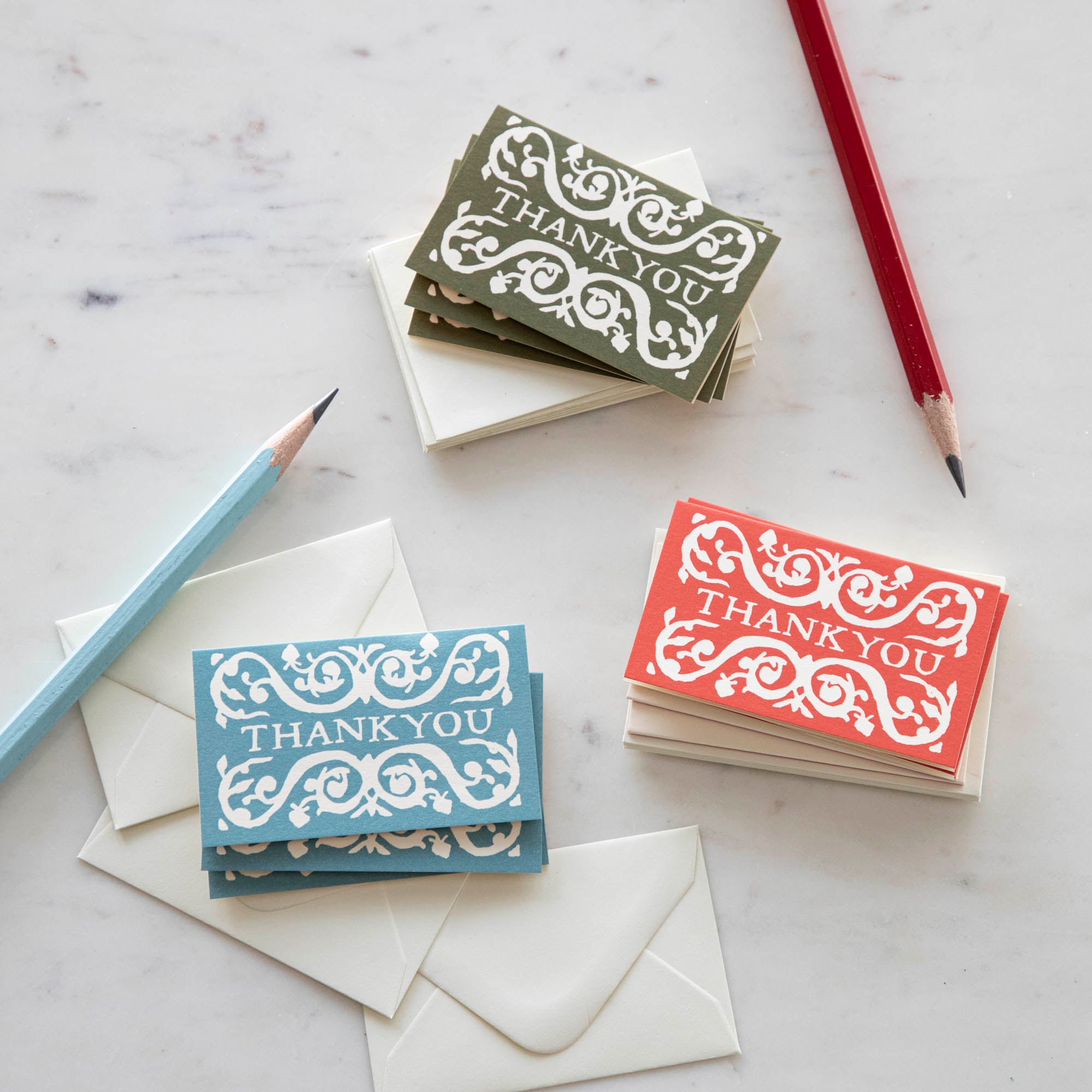 A selection of Cambridge Imprint Arabesque Thank You Cards with intricate designs next to two pencils, crafted on FSC-certified stock.
