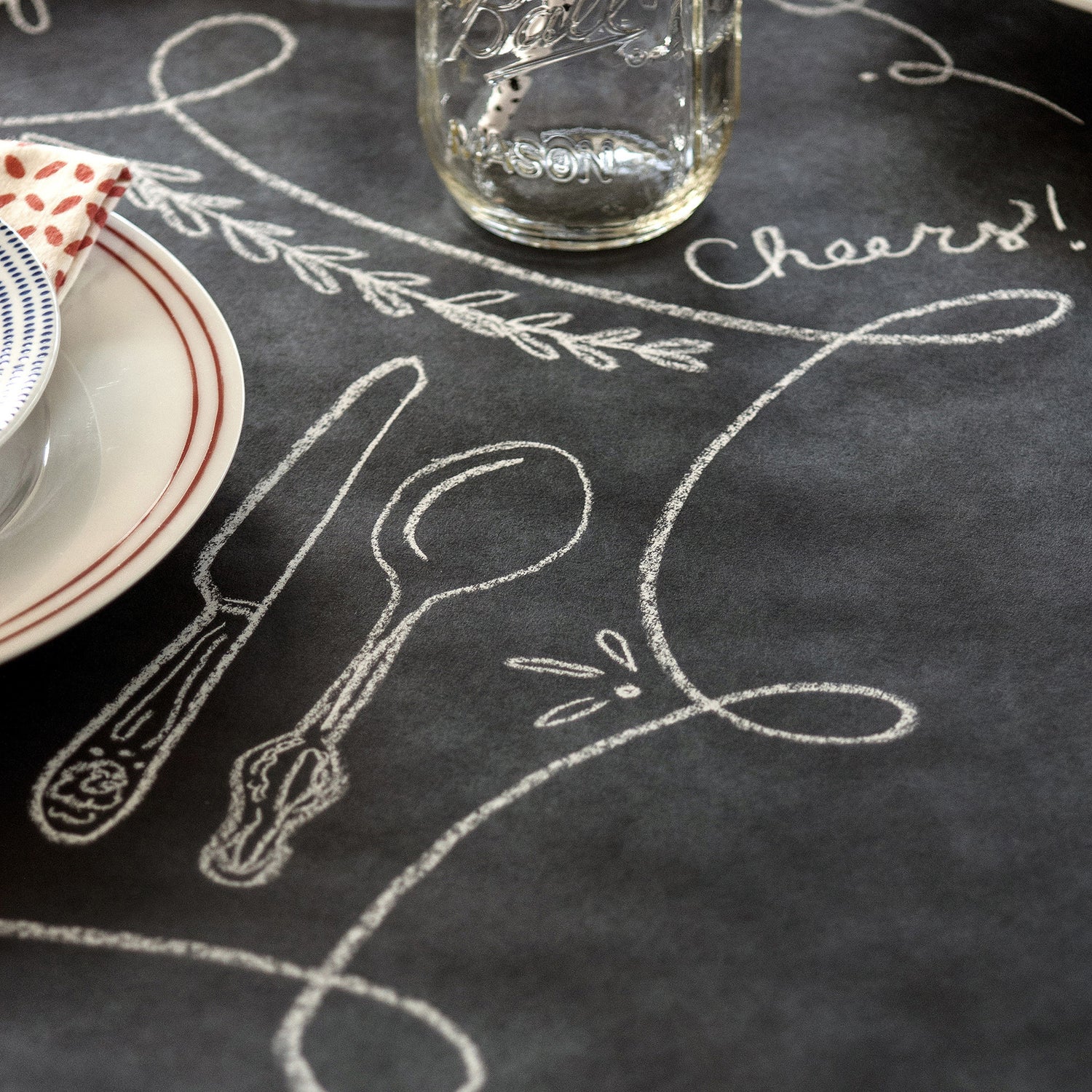 Close up of an elegant place setting on top of the Chalkboard Runner, showing hand-drawn embellishments around each plate.