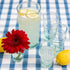 A pitcher of lemonade in a Clear Beldi Glassware on a blue and white checkered tablecloth.