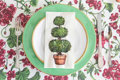 A green plate with a Hester &amp; Cook Topiary Napkins on it, perfect for a table setting at a party.