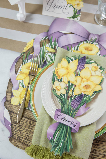 A floral place setting featuring a Daffodil Table Accent with &quot;Cheers&quot; written on the ribbon resting on the plate.