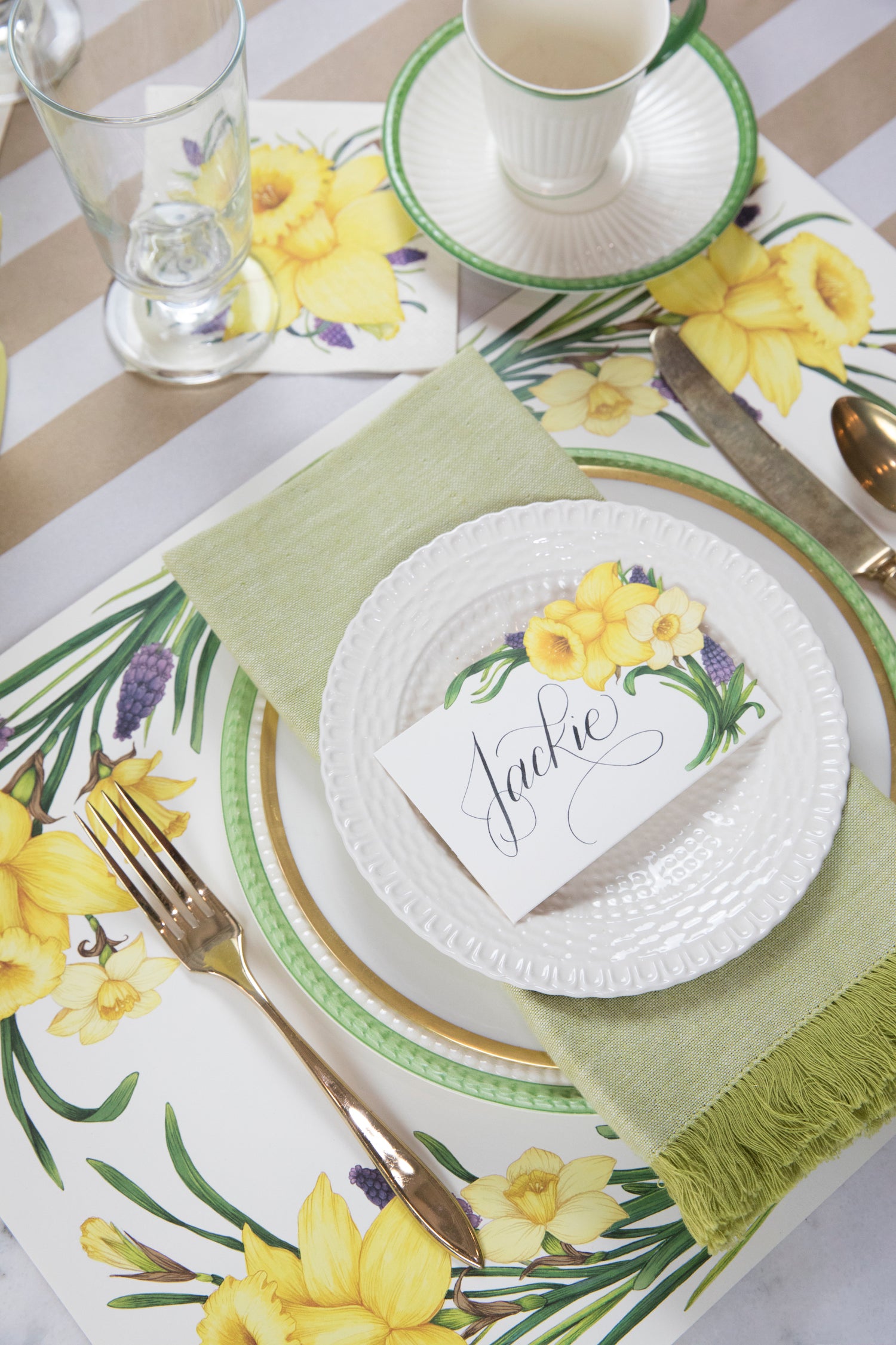 A spring-themed table setting with a Hester &amp; Cook Daffodil placemat, plate, and silverware.