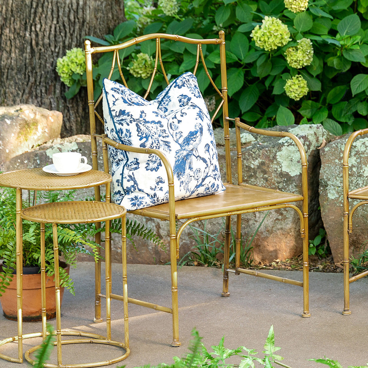 A Park Hill metal bamboo porch chair with a blue and white patterned cushion in a garden setting with a matching side table and cup.