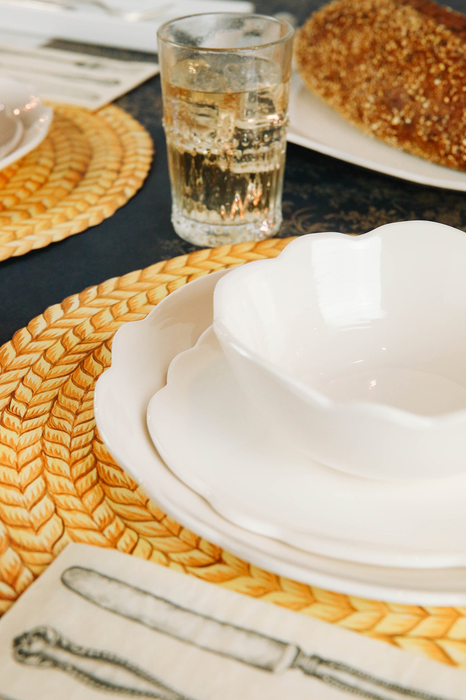 A sweet white Scallop Cream Dinner Plate with bread on it, made by Relish Dinnerware.