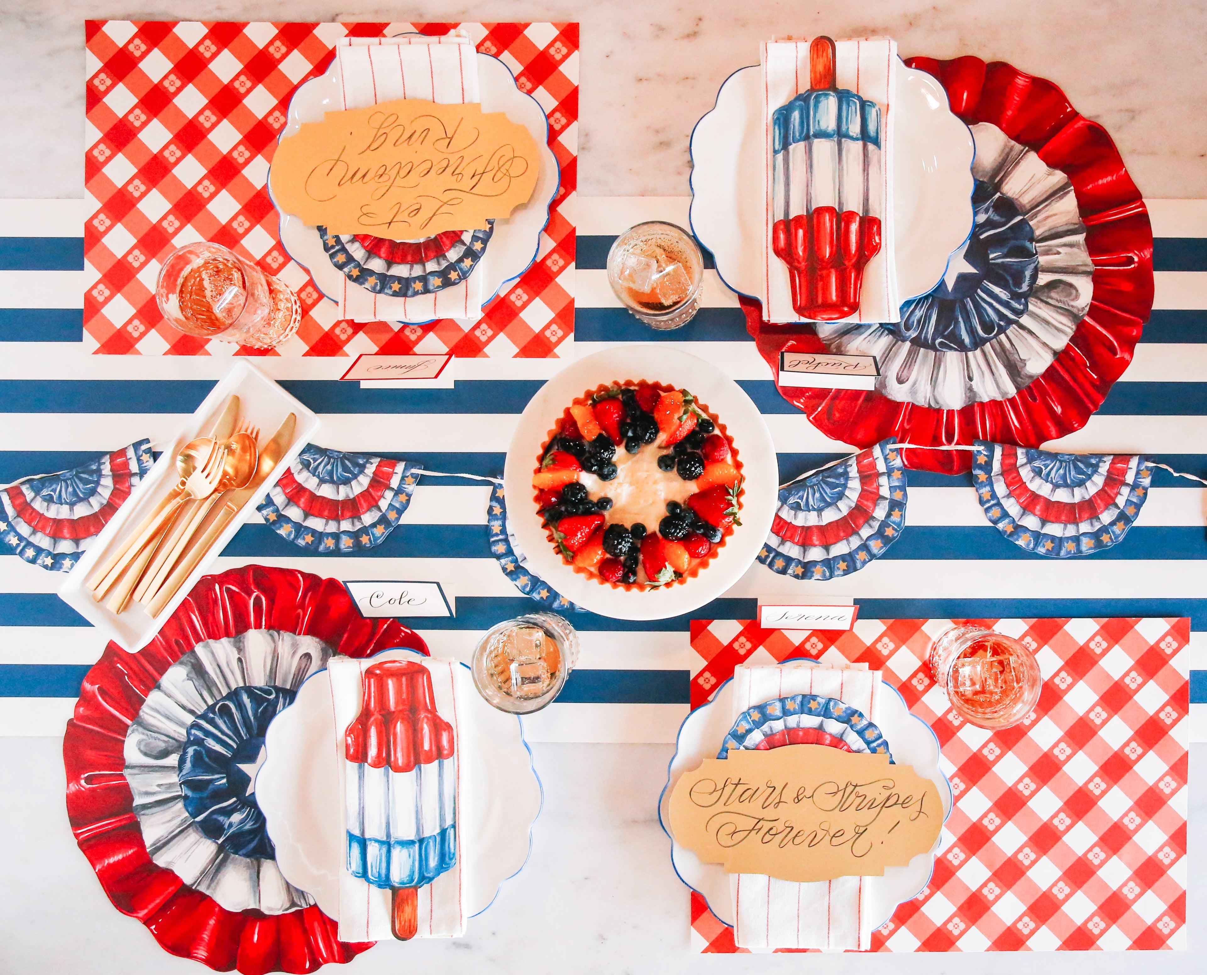 4th of July table setting with a pack of 12 Die-cut Star-Spangled Placemats by Hester &amp; Cook and red, white, and blue decorations.