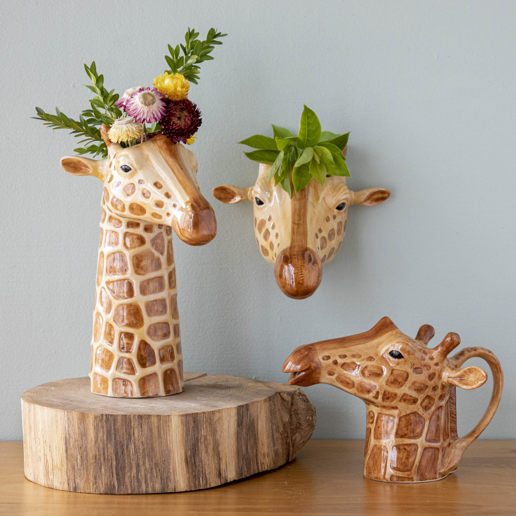 Three Quail Ceramic giraffe vases with flowers in them, created by the British brand Quail Ceramics.